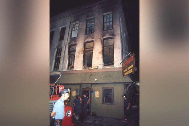 燃え尽きたバーとホテルを見上げる消防士と救助隊員